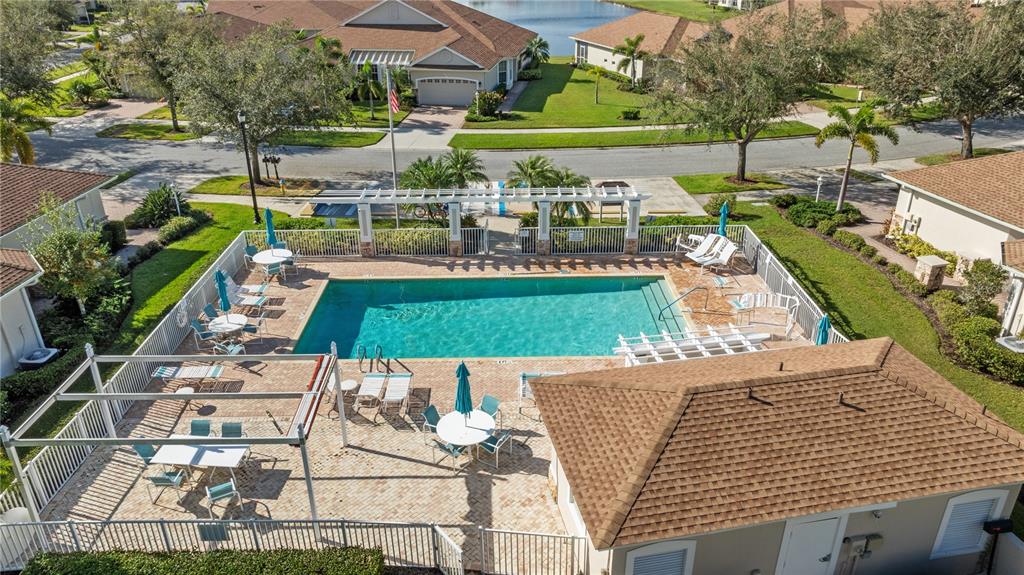 An aerial view of a community swimming pool with lounge chairs, umbrellas, and a pergola — 1937 SCARLETT AVENUE, NORTH PORT, FL