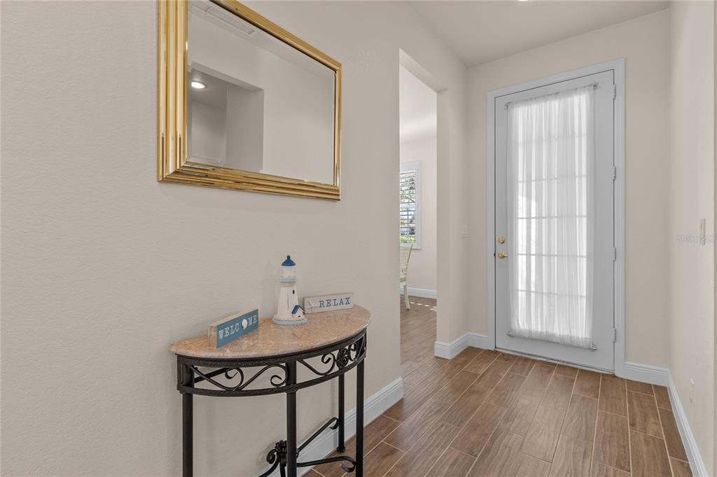 A foyer features a half-moon console table, a gold-framed mirror, and a glass-paneled door — 1937 SCARLETT AVENUE, NORTH PORT, FL