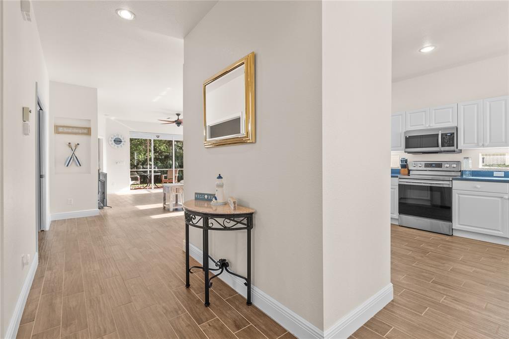 A hallway with a console table and mirror leads to a living area and kitchen — 1937 SCARLETT AVENUE, NORTH PORT, FL