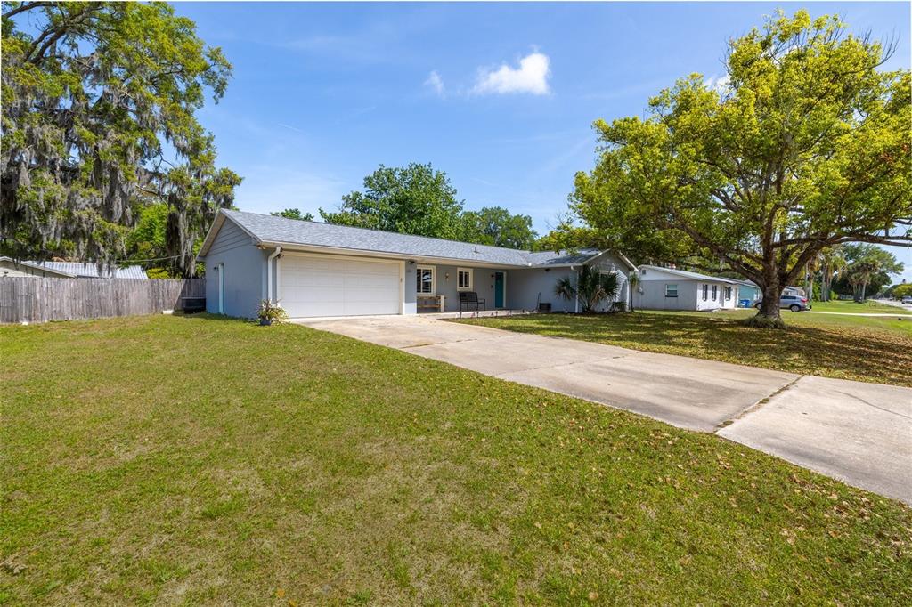 A single-story house with a gray exterior, a two-car garage, and a large front lawn — 1709 UMBRELLA TREE DRIVE, EDGEWATER, FL