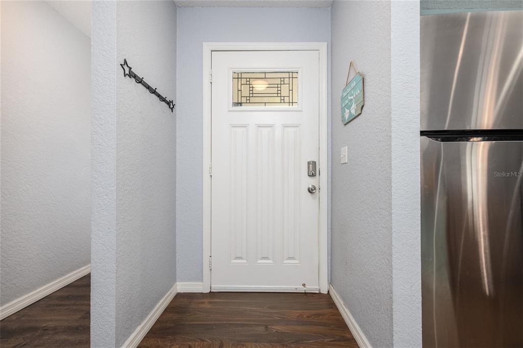 A white front door with a decorative glass window sits in a light blue entryway — 1709 UMBRELLA TREE DRIVE, EDGEWATER, FL