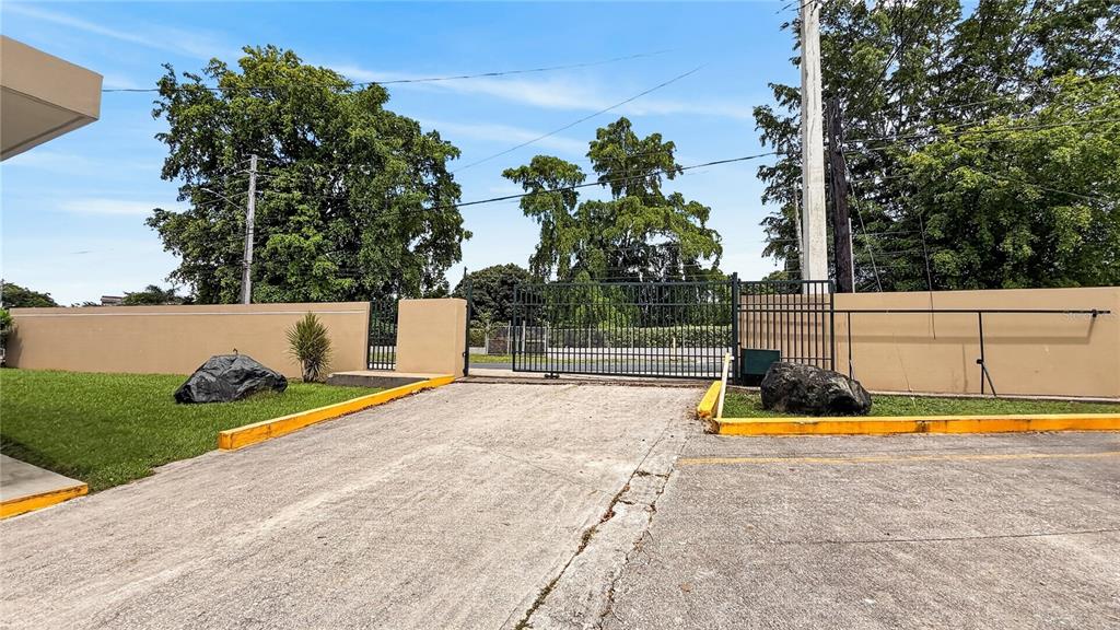 A paved driveway leads to a metal gate set within a tan wall and fence — 120 BO HATO TEJAS, BAYAMON, PR