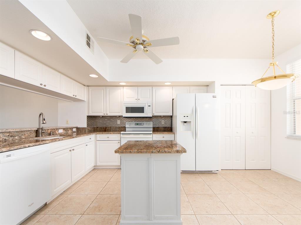 A kitchen with white cabinets, granite countertops, a center island, and white appliances — 6550 SHORELINE DRIVE UNIT 7502, ST PETERSBURG, FL