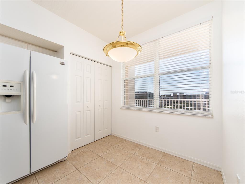 A kitchen dining area features a white refrigerator, a closet, tile floors, and a pendant light — 6550 SHORELINE DRIVE UNIT 7502, ST PETERSBURG, FL