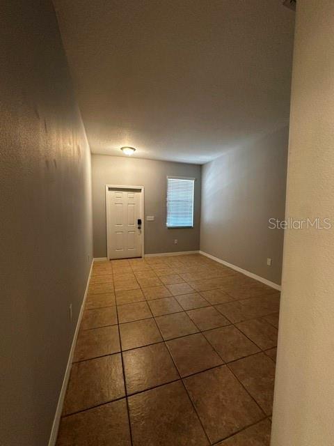 An empty room with light gray walls, a white door, and brown tiled flooring — 11213 SAVANNAH LANDING CIRCLE, ORLANDO, FL