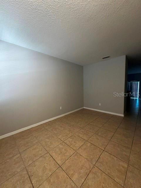 An empty room features light gray walls, white baseboards, and tan tile flooring — 11213 SAVANNAH LANDING CIRCLE, ORLANDO, FL