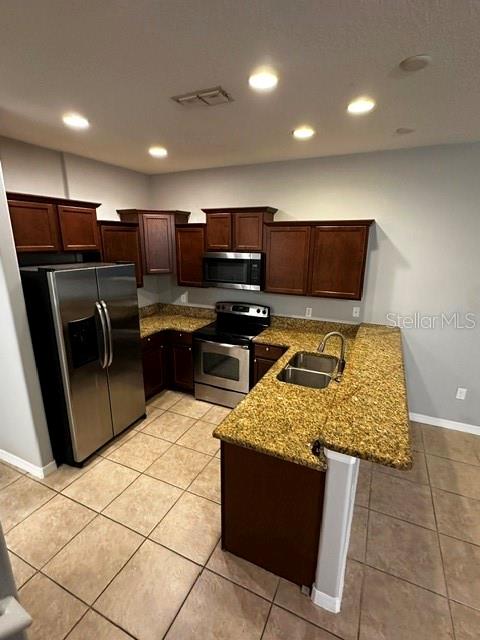 A kitchen features dark wood cabinets, granite countertops, stainless steel appliances, and tile flooring — 11213 SAVANNAH LANDING CIRCLE, ORLANDO, FL