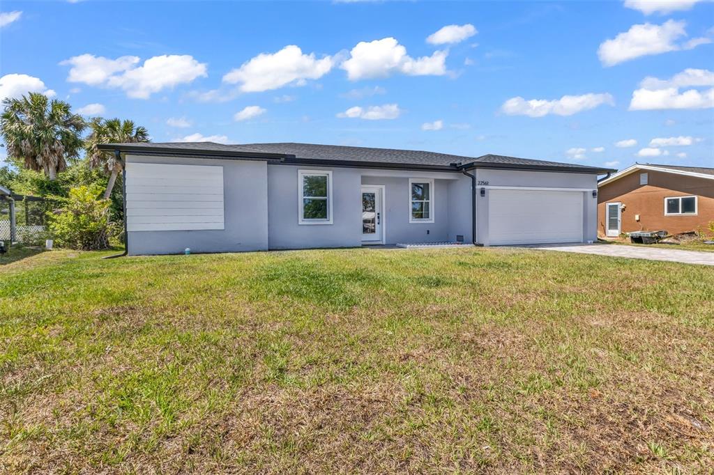 A single-story gray house with a two-car garage and a large front lawn — 22561 ALCORN AVENUE, PORT CHARLOTTE, FL