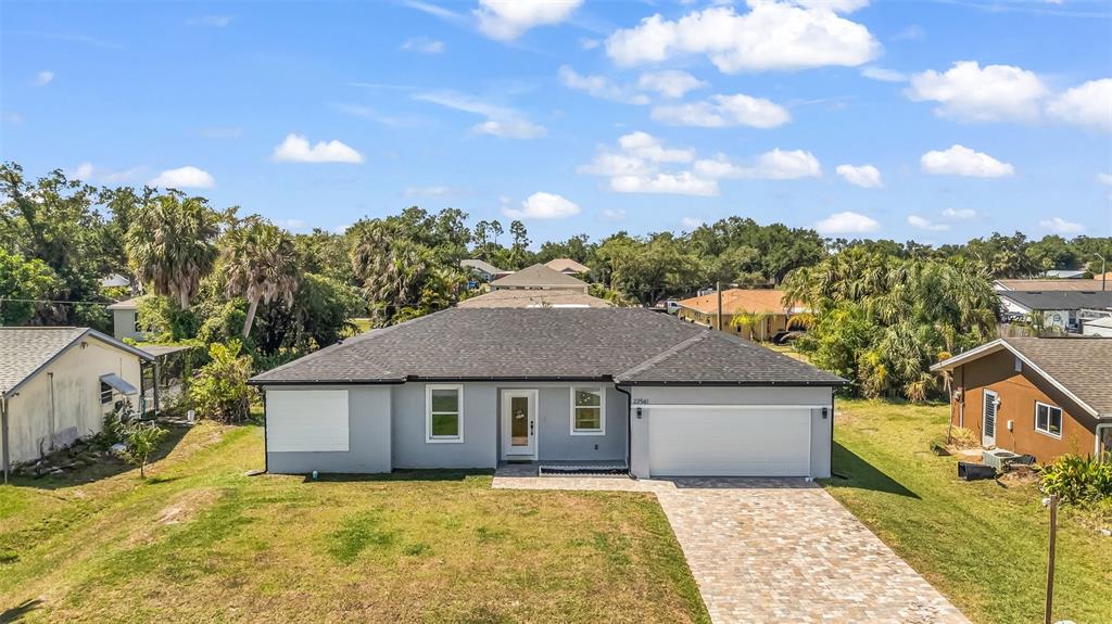 A single-story gray house with a dark roof, white garage door, and paved driveway — 22561 ALCORN AVENUE, PORT CHARLOTTE, FL