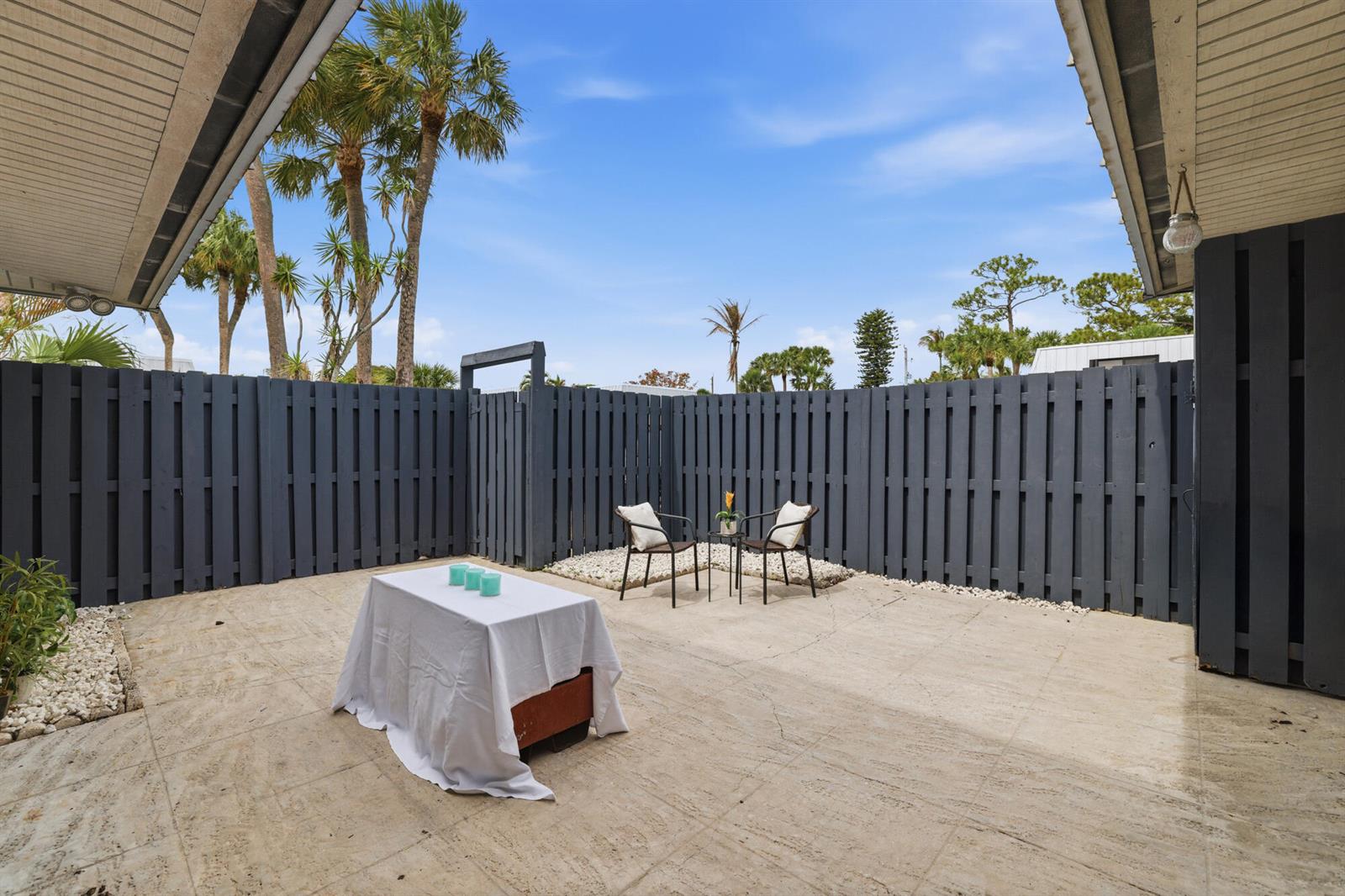 A private outdoor patio features a concrete floor, dark gray fencing, and a small seating area — 3832 SE Jefferson Street, Stuart FL 34997, STUART, FL