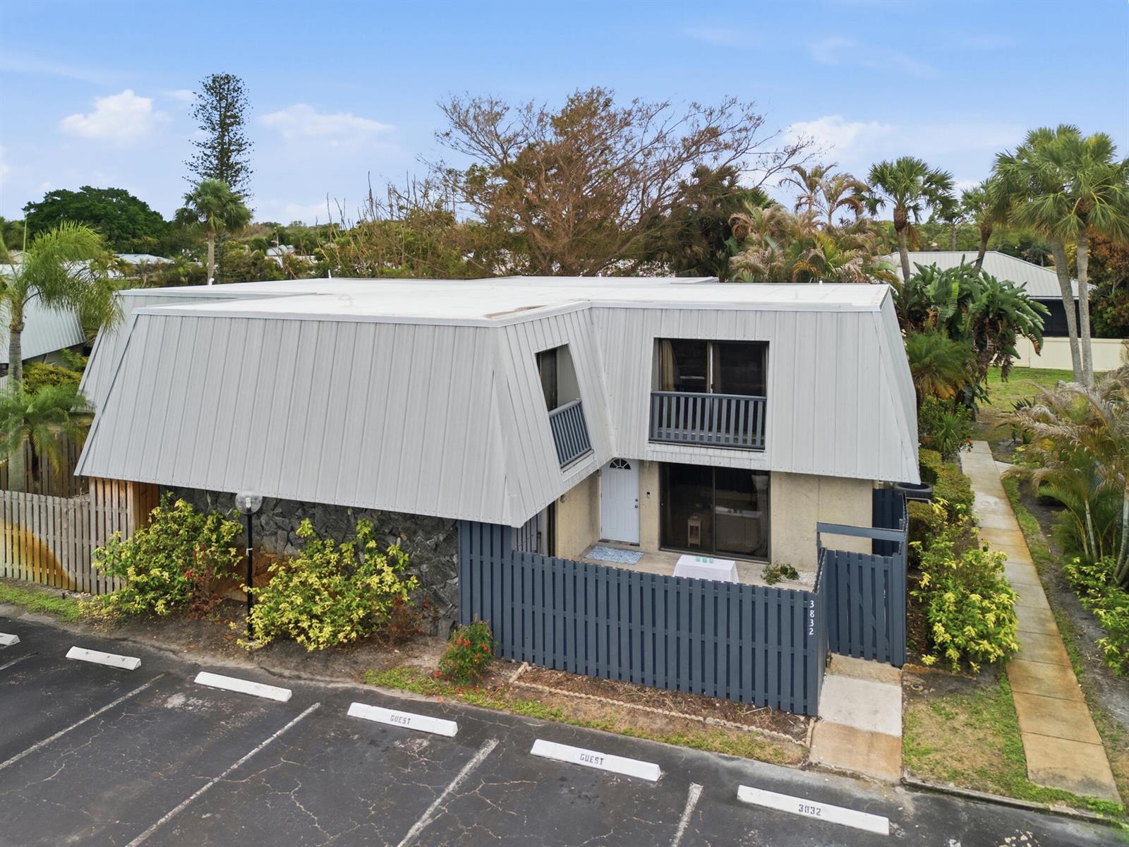 An exterior view of a two-story building with a gray mansard roof and fenced patio — 3832 SE Jefferson Street, Stuart FL 34997, STUART, FL
