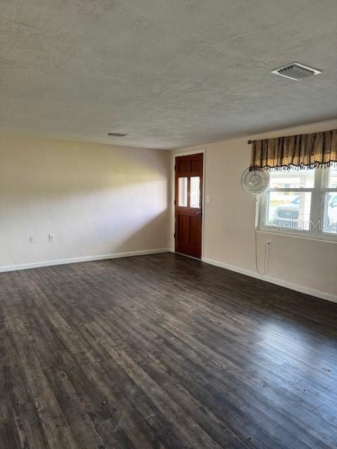 An empty room features dark wood-look flooring, a brown door, and a window with valance — 95 S FILLMORE STREET, BEVERLY HILLS, FL