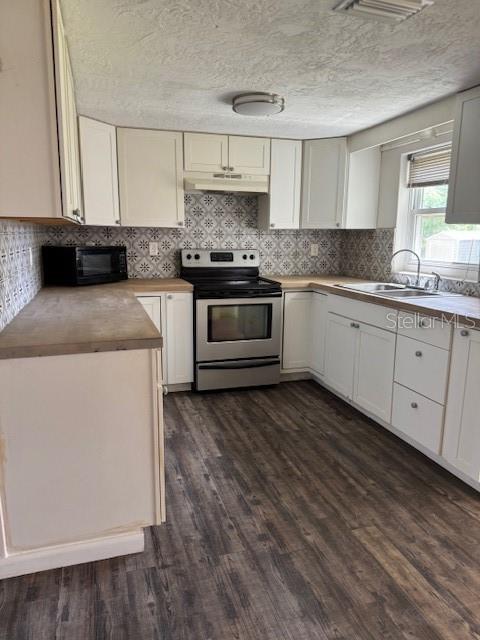 A kitchen features white cabinets, a stainless steel stove, and wood-look flooring — 95 S FILLMORE STREET, BEVERLY HILLS, FL