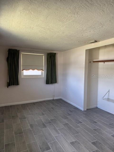 A bedroom features gray wood-look tile flooring, a window with curtains, and an open closet — 95 S FILLMORE STREET, BEVERLY HILLS, FL