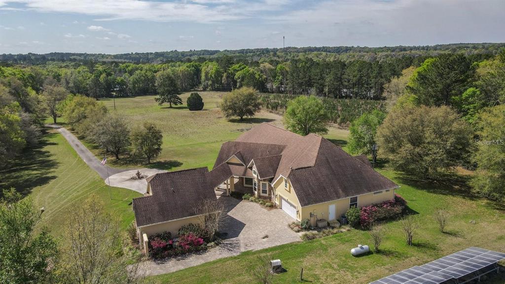 An aerial view shows a large house with a detached garage and solar panels — 18604 NW 262ND AVENUE, ALACHUA, FL