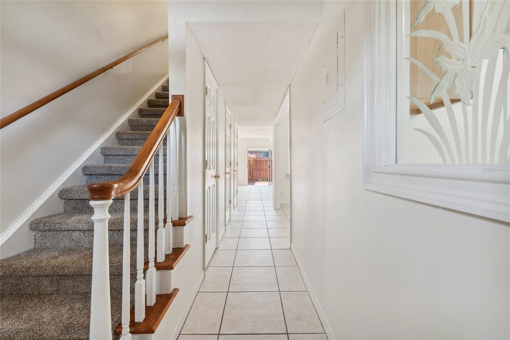 A hallway with tiled floors leads to a doorway, with a carpeted staircase on the left — 316 GEORGETOWN DRIVE UNIT 316, CASSELBERRY, FL