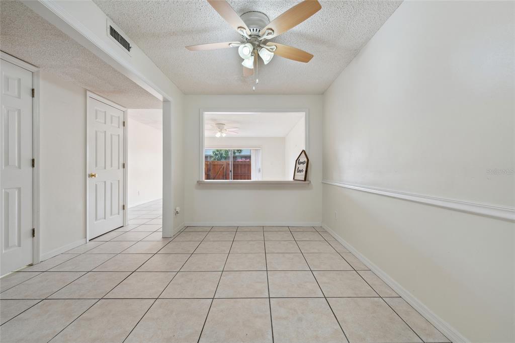 A dining area features light-colored tile flooring, a ceiling fan, and a pass-through window — 316 GEORGETOWN DRIVE UNIT 316, CASSELBERRY, FL