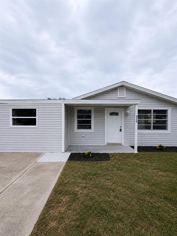 A single-story house with light gray siding, a covered porch, and a concrete driveway — 4112 MESA DRIVE, NEW PORT RICHEY, FL
