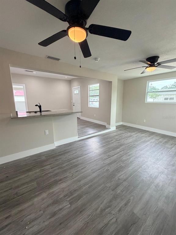 A living room with gray wood-look flooring, a ceiling fan, and a kitchen pass-through window — 4112 MESA DRIVE, NEW PORT RICHEY, FL