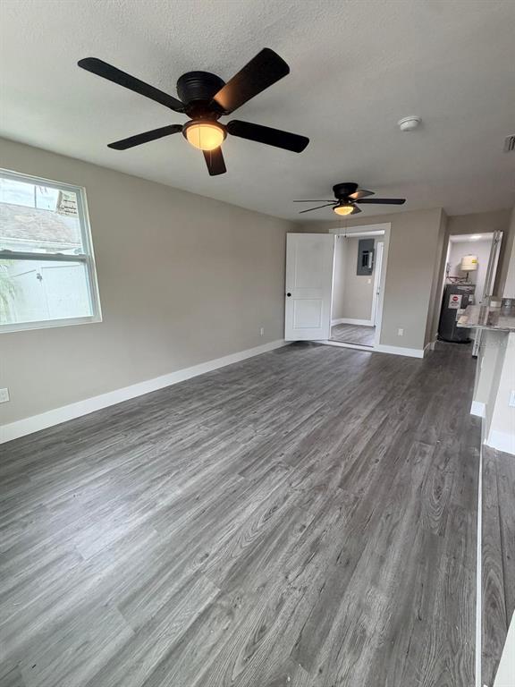 A room with gray wood-look flooring, two ceiling fans, and an open doorway — 4112 MESA DRIVE, NEW PORT RICHEY, FL