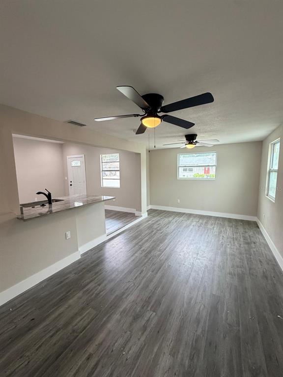 A living room with gray wood-look flooring, two ceiling fans, and a kitchen breakfast bar — 4112 MESA DRIVE, NEW PORT RICHEY, FL