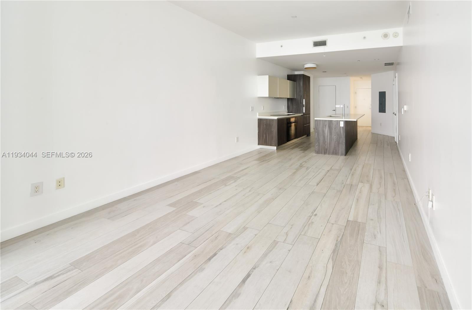 An open-concept living area features light wood-look flooring and a modern kitchen with dark cabinetry — 480 NE 31st St # 3405, Miami FL 33137, MIAMI, FL
