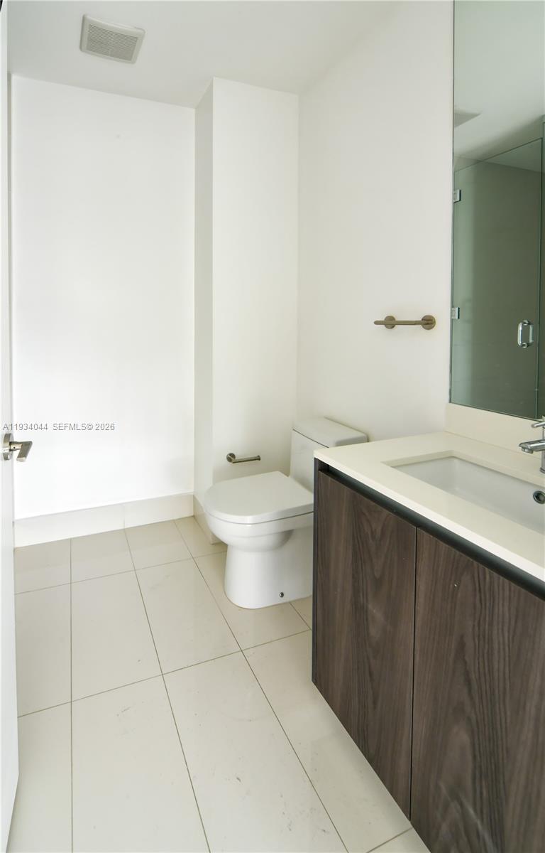 A modern bathroom features a white toilet, a vanity with a sink, and tiled flooring — 480 NE 31st St # 3405, Miami FL 33137, MIAMI, FL