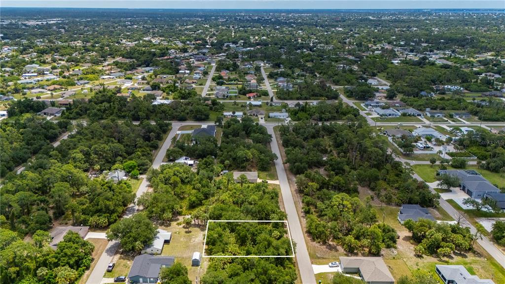 An aerial view shows a rectangular, wooded vacant lot outlined in white along a paved road — 17464 BILLIAR AVENUE, PORT CHARLOTTE, FL