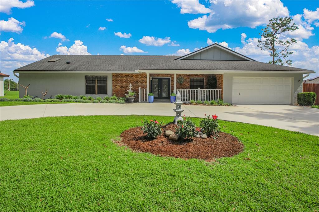 A single-story house with a brick facade, white garage, and a circular driveway — 7243 WOODVILLE CRESCENT, ORLANDO, FL