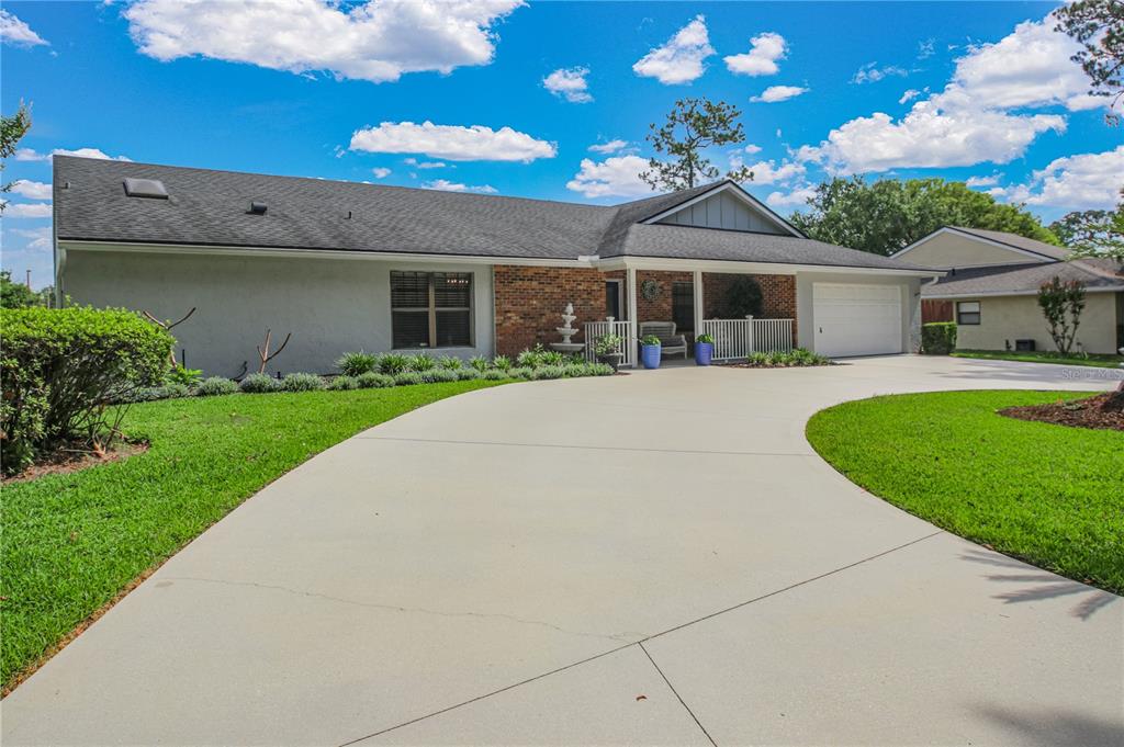 A single-story house with a brick facade, gray stucco walls, and a large concrete driveway — 7243 WOODVILLE CRESCENT, ORLANDO, FL