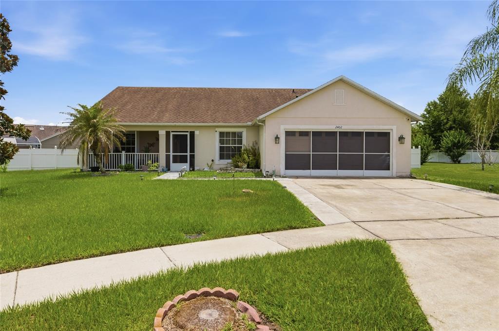 A single-story house with a beige stucco exterior, a two-car garage, and a front porch — 2402 ACCORD TERRACE, KISSIMMEE, FL