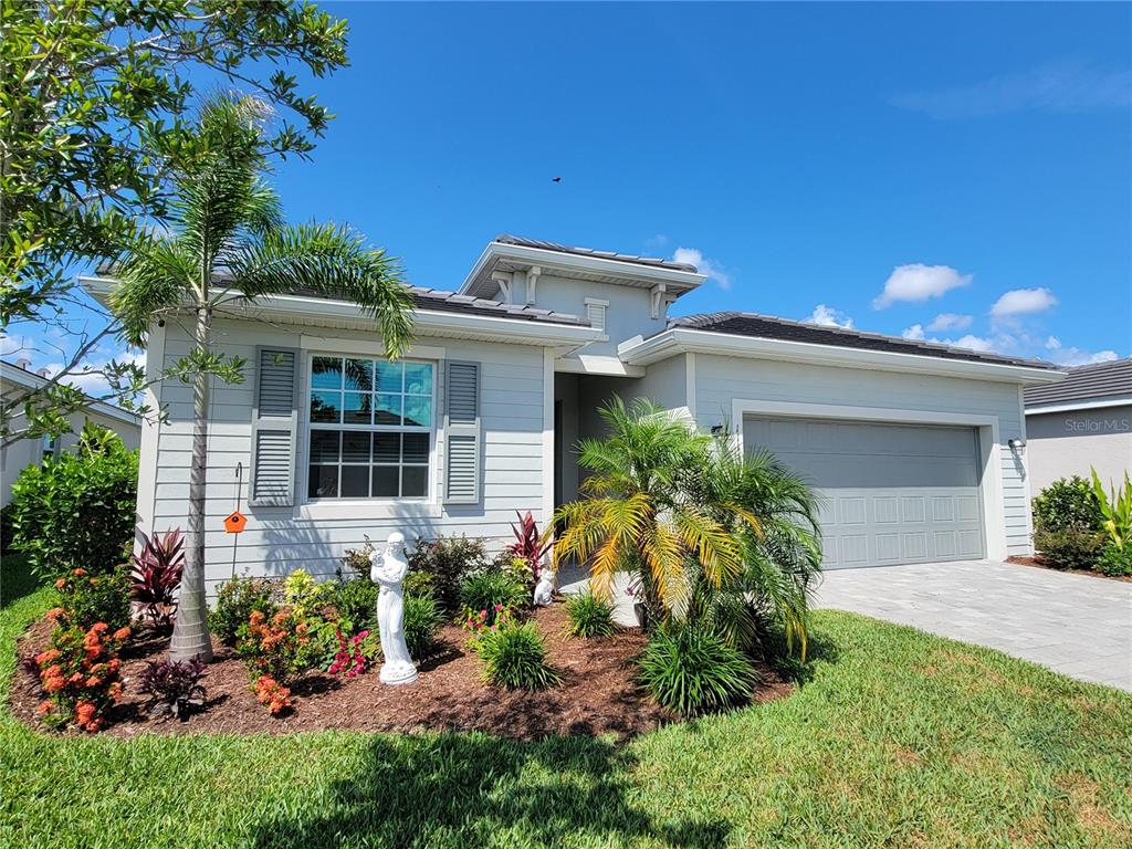 A light-colored single-story house with a two-car garage and a landscaped front yard — 11177 PINOT DRIVE, VENICE, FL