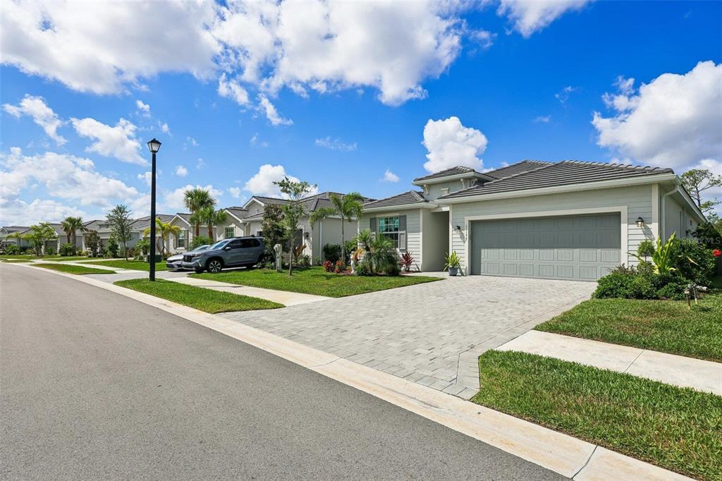 A light-colored single-story house with a paved driveway and a two-car garage — 11177 PINOT DRIVE, VENICE, FL