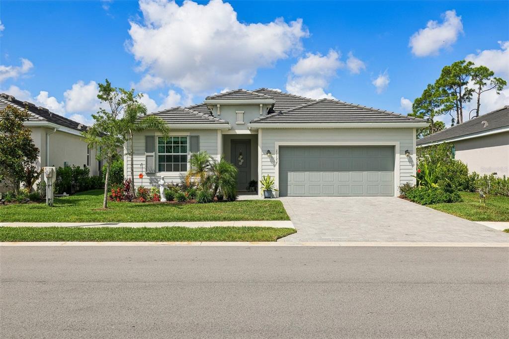 A single-story suburban house with a gray tiled roof, light siding, and a two-car garage — 11177 PINOT DRIVE, VENICE, FL