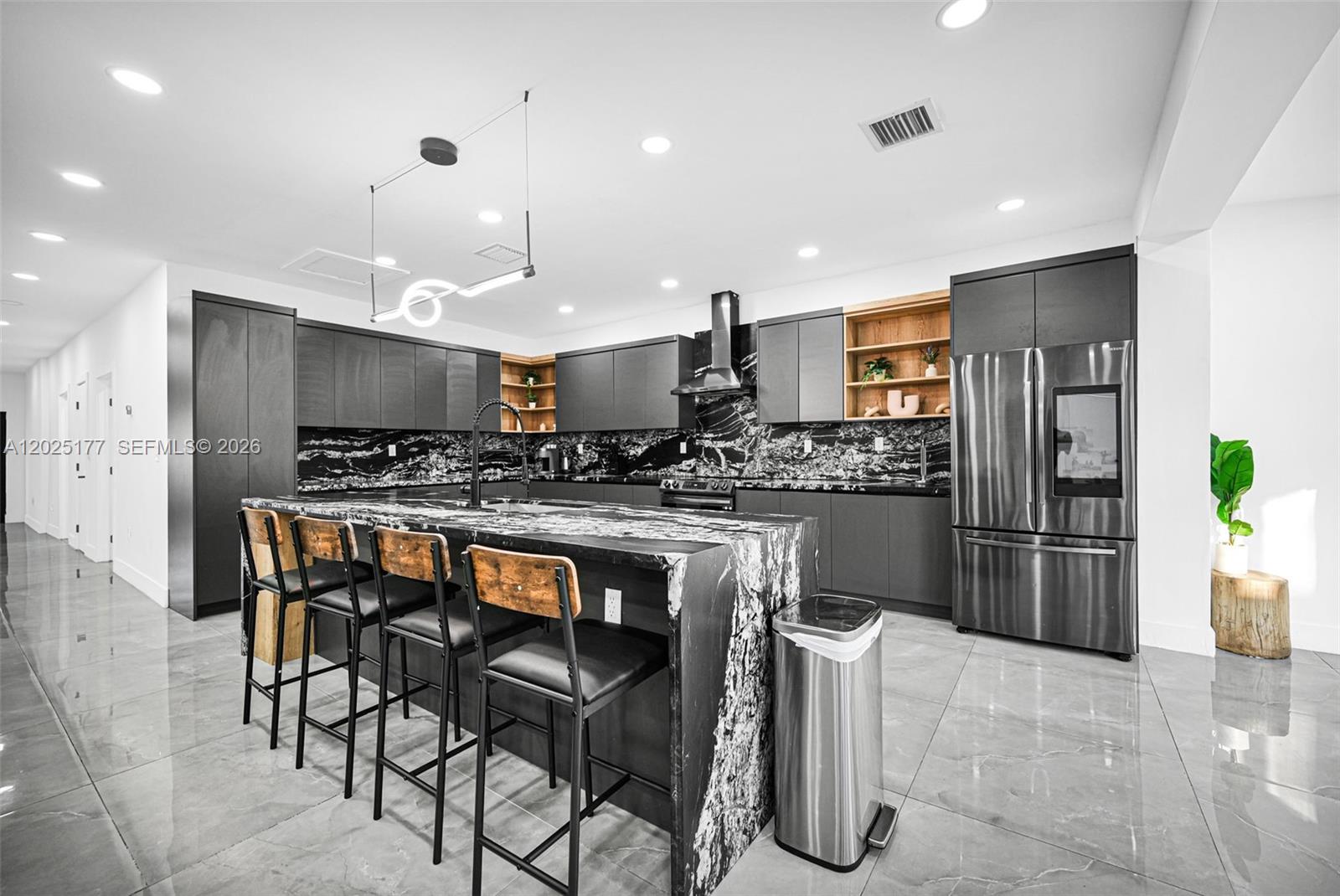 A modern kitchen features dark cabinetry, black and white marble countertops, and a matching island — 112 NW 53rd St, Miami FL 33127, MIAMI, FL
