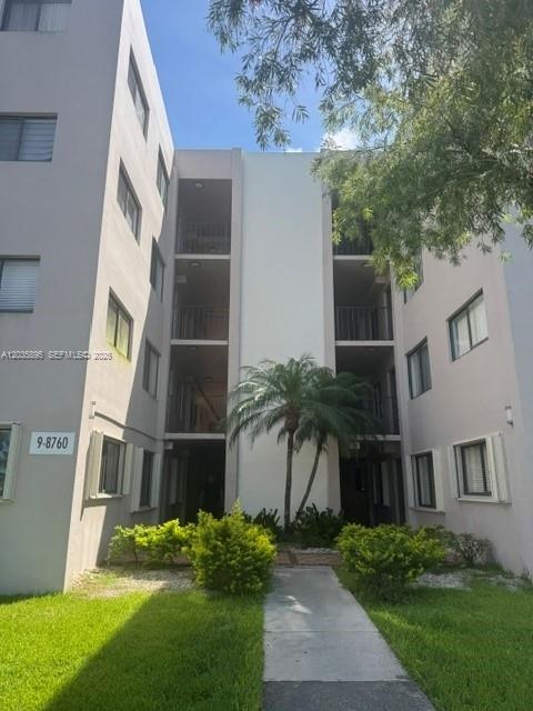 A low-rise apartment building exterior features a central walkway, balconies, and surrounding landscaping — 8760 SW 133rd Ave Rd # 107, Miami FL 33183, MIAMI, FL