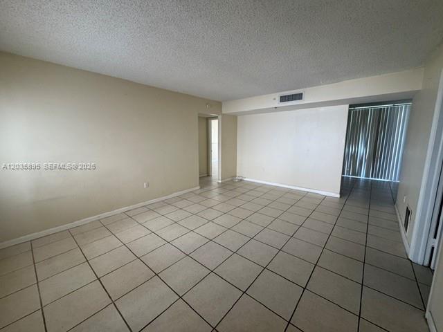 An empty room features beige tiled flooring, light-colored walls, and a sliding glass door — 8760 SW 133rd Ave Rd # 107, Miami FL 33183, MIAMI, FL