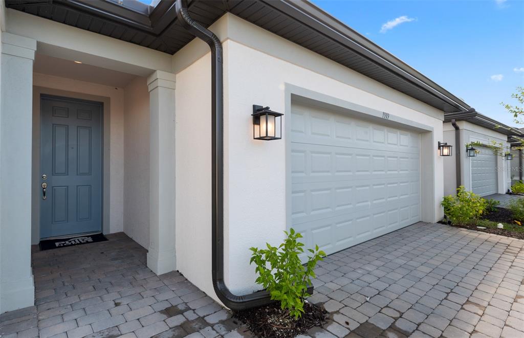 A light-colored house exterior features a blue front door, a garage, and a paved driveway — 4620 BLUE STAR COURT, NORTH PORT, FL