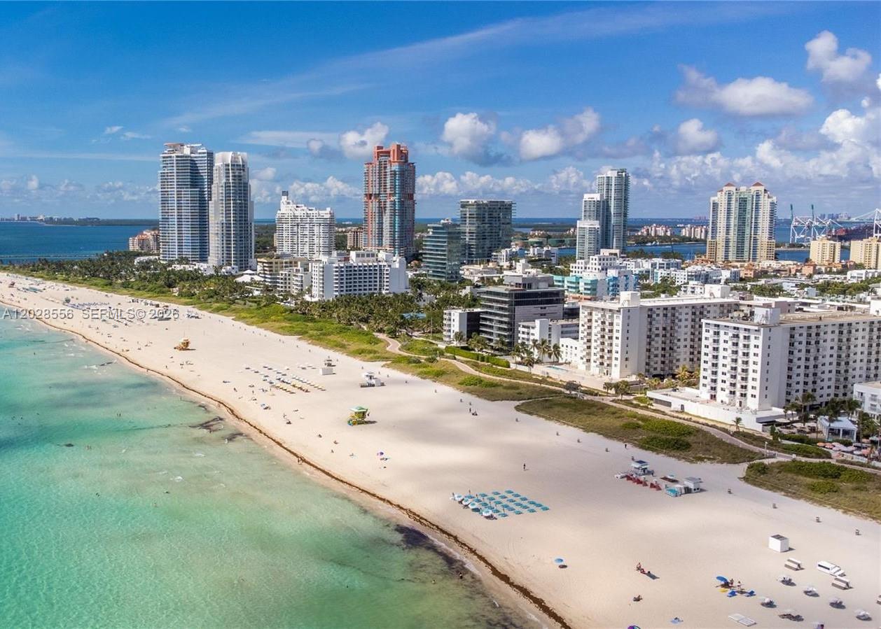 An aerial view of a sandy beach with turquoise water and high-rise buildings in Miami — 345 Ocean Dr # 602, Miami Beach FL 33139, MIAMI BEACH, FL