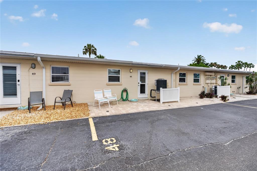 The exterior of a single-story residential building features tan siding, paved patios, and parking spaces — 5830 MIDNIGHT PASS ROAD UNIT 48, SARASOTA, FL