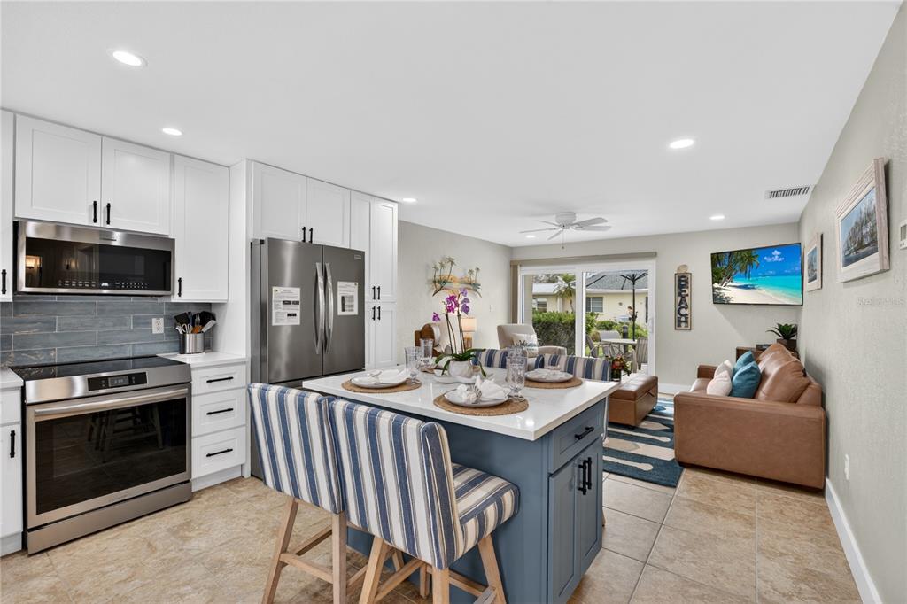 A kitchen with white cabinets and a blue island opens into a living area — 5830 MIDNIGHT PASS ROAD UNIT 48, SARASOTA, FL