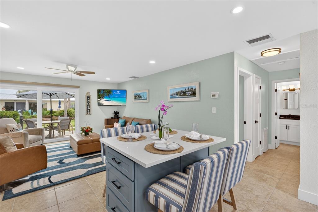 A kitchen island with blue cabinets and striped chairs sits in an open-concept living area — 5830 MIDNIGHT PASS ROAD UNIT 48, SARASOTA, FL