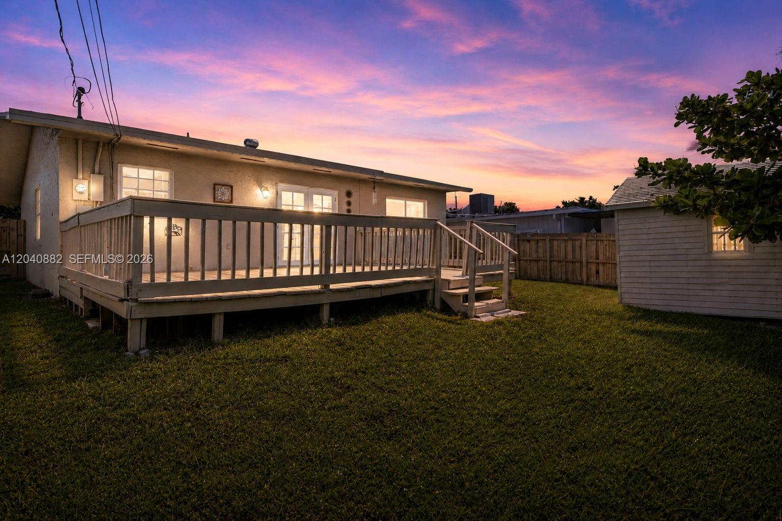 A wooden deck extends from the back of a house into a grassy backyard — 816 Johnson St, Hollywood FL 33019, HOLLYWOOD, FL