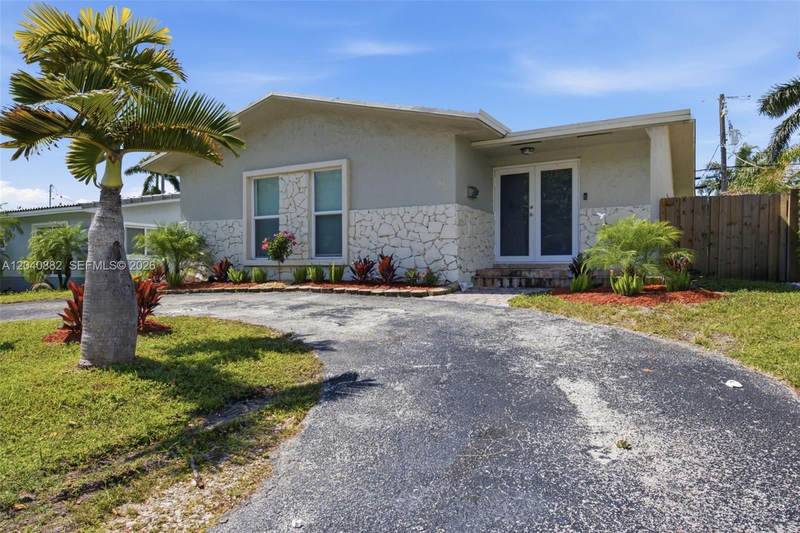A single-story house features a stone facade, a curved driveway, and a prominent palm tree — 816 Johnson St, Hollywood FL 33019, HOLLYWOOD, FL