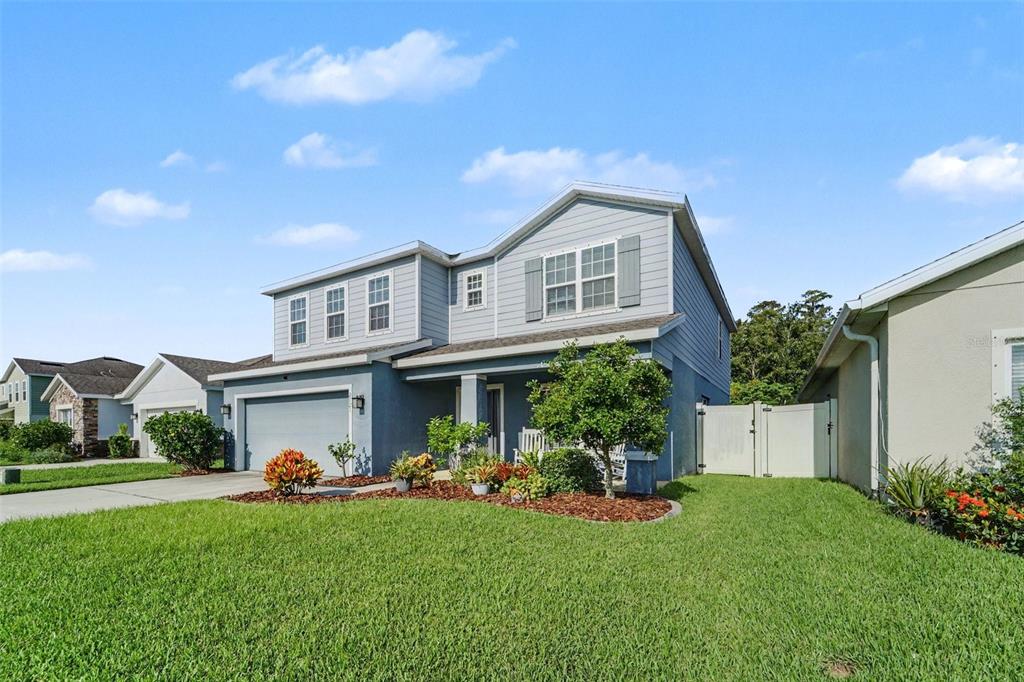 A two-story blue house with a two-car garage and a landscaped front yard — 2121 BRANDING IRON COURT, TRINITY, FL