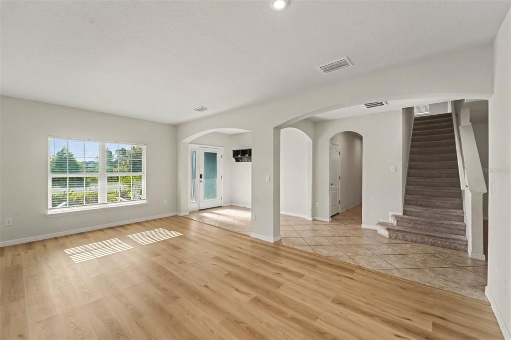 An interior view shows a living room with wood-look flooring, a staircase, and tiled entryway — 2121 BRANDING IRON COURT, TRINITY, FL