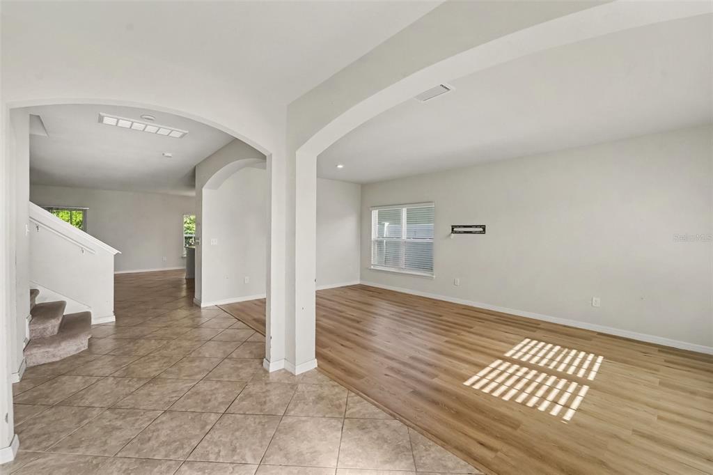 An interior view showing a tiled entryway, carpeted stairs, and a living area with wood flooring — 2121 BRANDING IRON COURT, TRINITY, FL