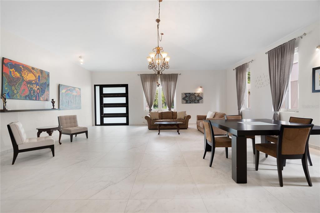 A spacious, open-concept living and dining area features white tile floors and a central chandelier — 840 MALAGA, GUAYNABO, PR
