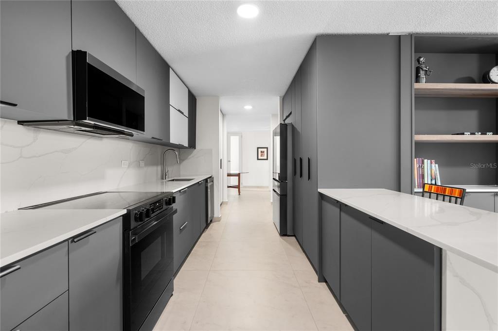 A modern galley kitchen features dark gray cabinetry, white countertops, and stainless steel appliances — 840 MALAGA, GUAYNABO, PR