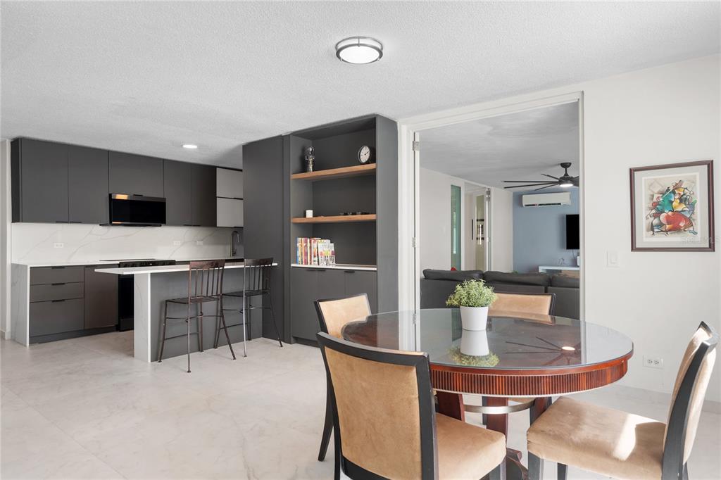 A kitchen with dark cabinets and an island sits beside a dining area with chairs — 840 MALAGA, GUAYNABO, PR